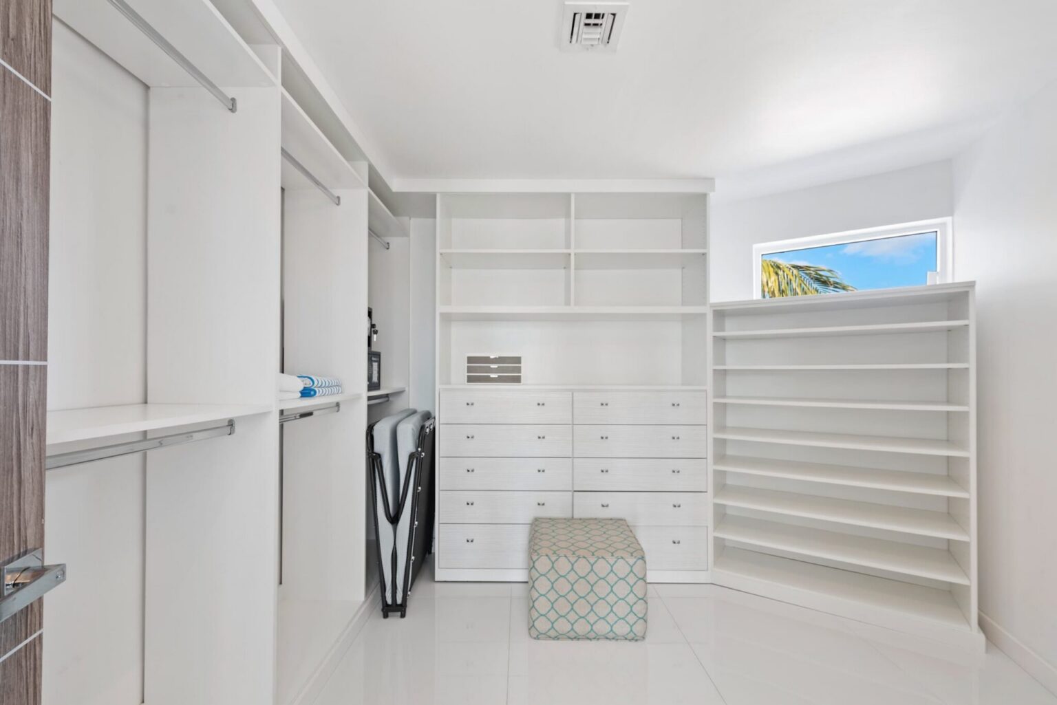 Dedicated laundry room featuring a full-size washer and dryer, built-in shelving, storage drawers, hanging space, and organized linen storage. Bright utility area designed for extended stays and convenient household functionality.