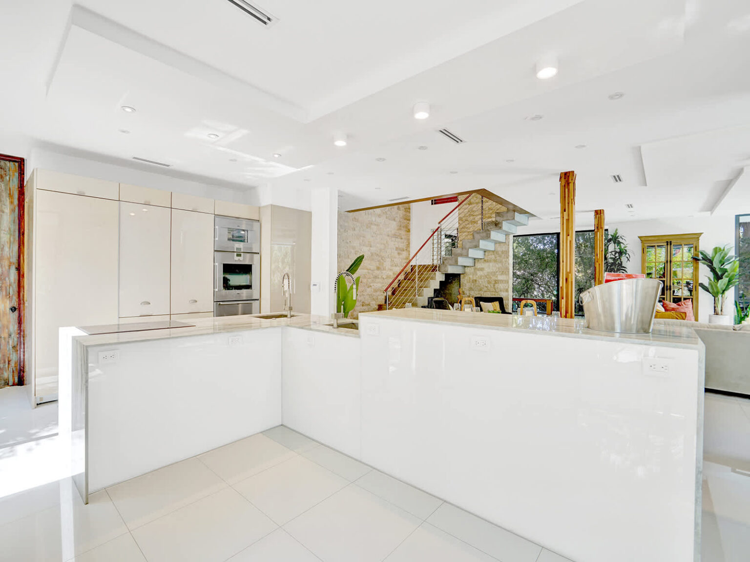 Contemporary kitchen with a large peninsula island, sleek white cabinetry, and integrated appliances. Recessed lighting and open sightlines connect the space to the living and dining areas, creating a bright and functional layout.