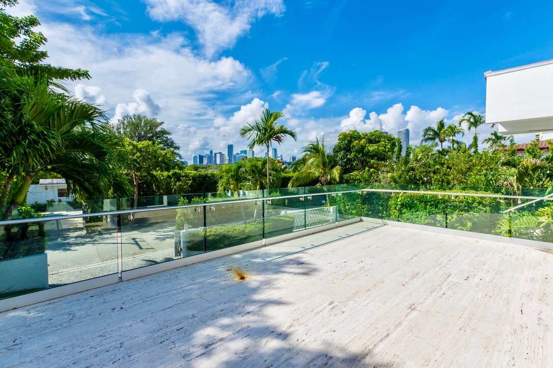 Expansive rooftop terrace featuring a large outdoor deck, glass railing system, panoramic tropical views, landscaped surroundings, and ample space for outdoor seating, entertaining, sunbathing, or enjoying the open-air setting above the property.