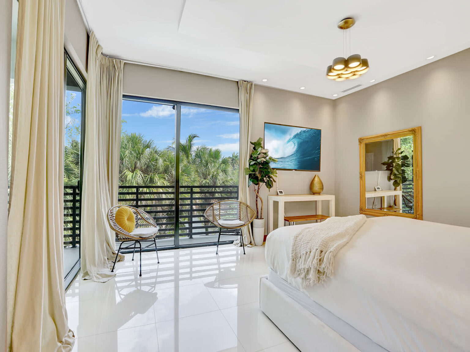 Bright bedroom featuring a king-size bed, floor-to-ceiling windows, and direct access to a private balcony with tropical views. Natural light, modern furnishings, and an open layout create a comfortable and inviting retreat.