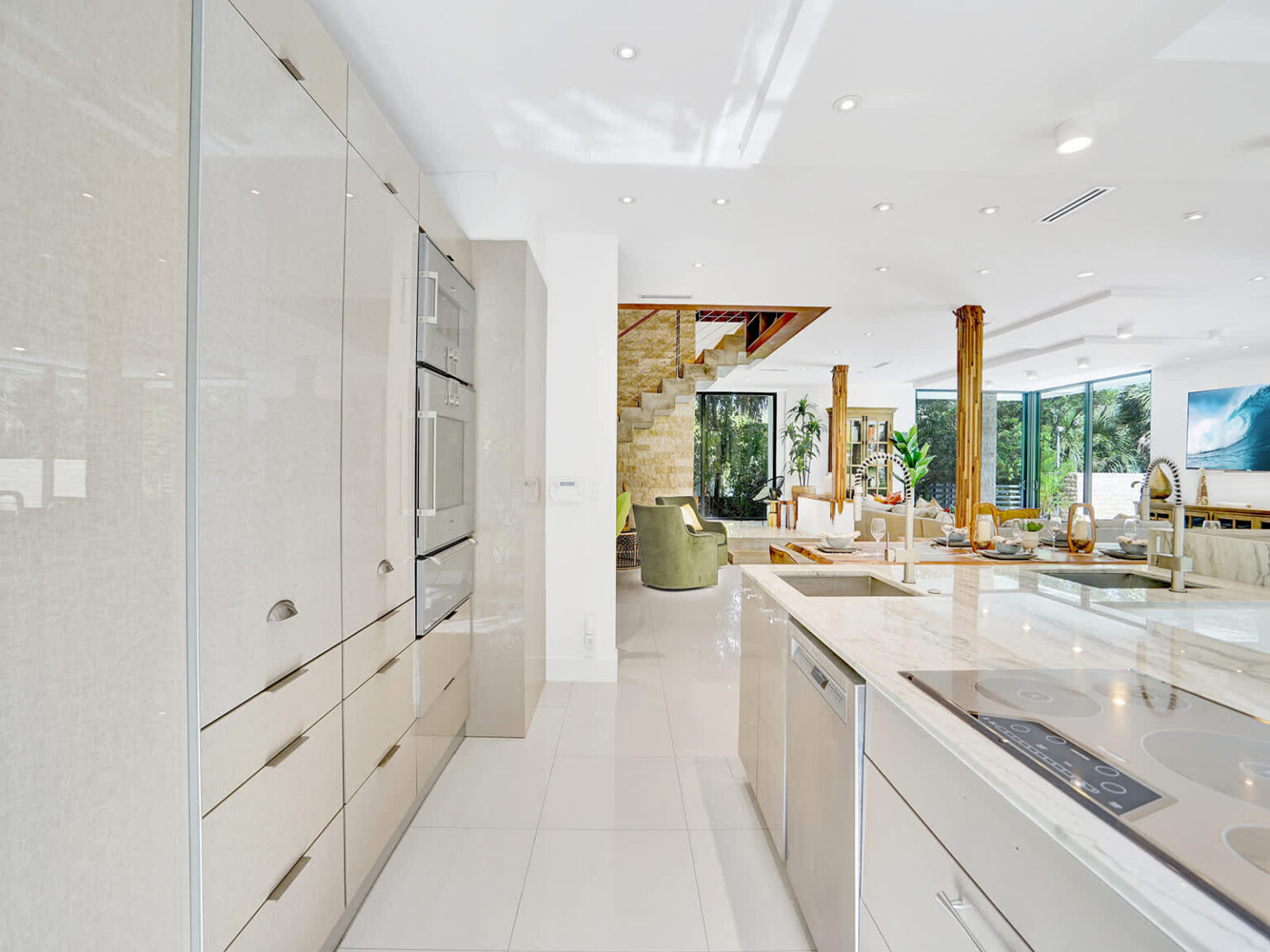 Modern galley-style kitchen with sleek cabinetry, integrated appliances, and expansive counter space. Large windows bring in natural light and tropical views, while the open layout provides seamless access to the dining and living areas.