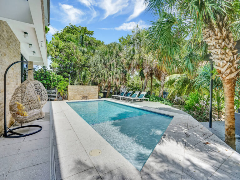 Private rectangular swimming pool with a spacious tiled sun deck, mature palm trees, and tropical greenery. Features multiple lounge chairs, garden privacy, and direct villa access, creating a tranquil resort-style outdoor setting.