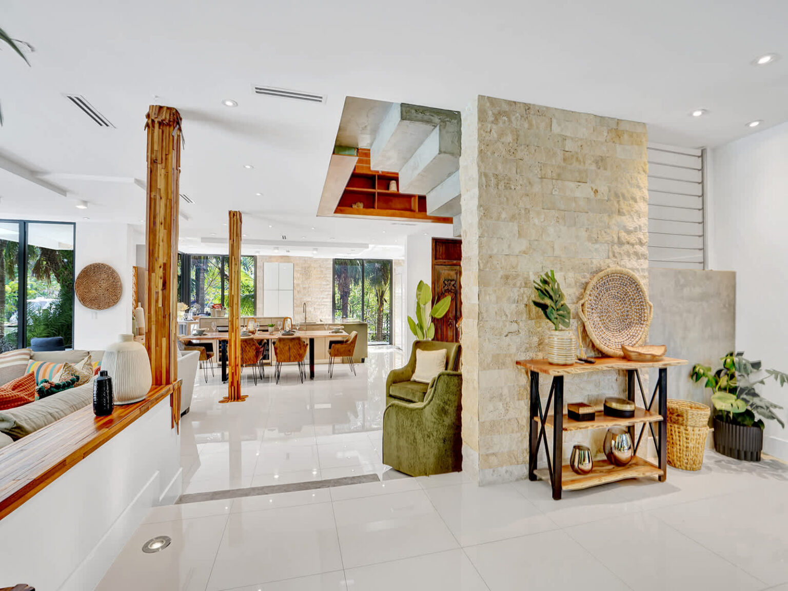 Open-concept living space with polished tile flooring, natural stone accent walls, and modern furnishings. Features high ceilings, abundant natural light, decorative wood details, and seamless access to surrounding indoor and outdoor areas.