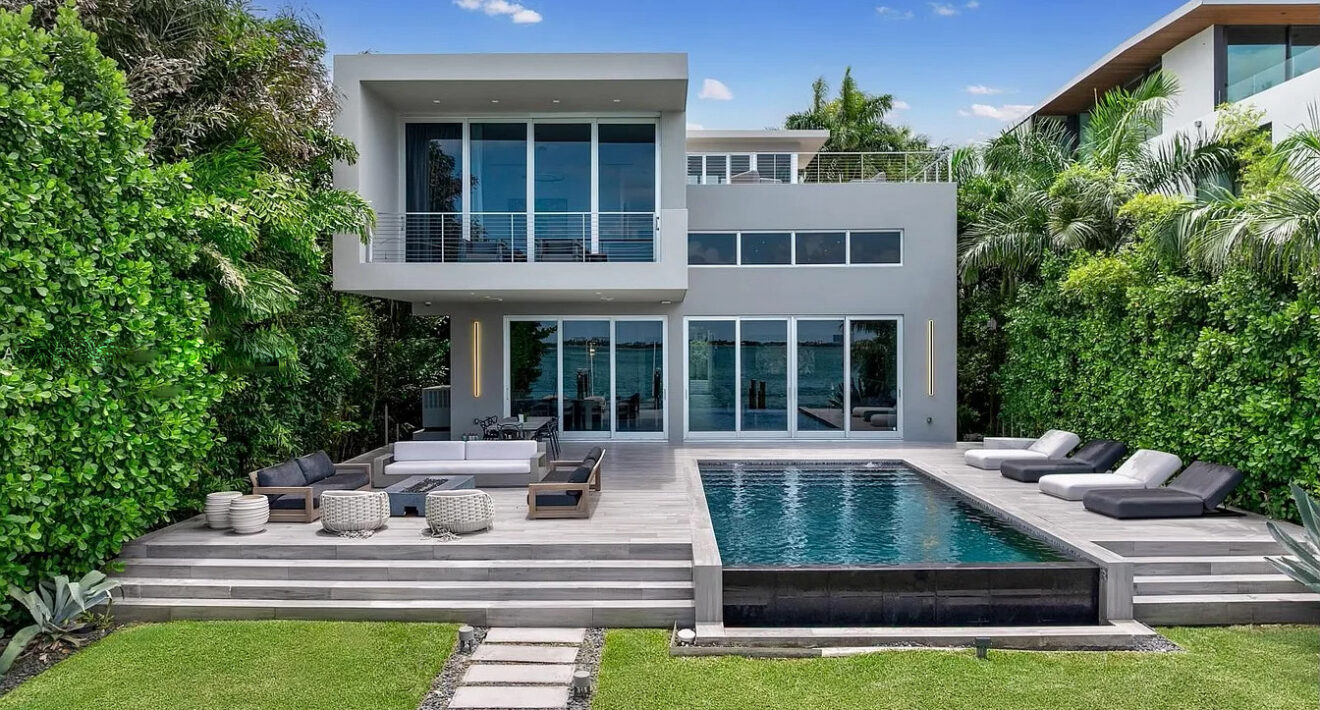 Modern waterfront luxury villa in Miami featuring a private pool, expansive terrace, lush tropical landscaping, and panoramic bay views.