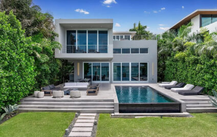 Modern waterfront luxury villa in Miami featuring a private pool, expansive terrace, lush tropical landscaping, and panoramic bay views.