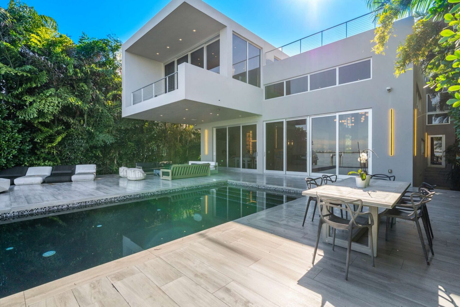 Private pool courtyard with outdoor dining, expansive decking, and contemporary architecture. Floor-to-ceiling glass doors create seamless indoor-outdoor living and easy access to the home's main entertaining spaces.