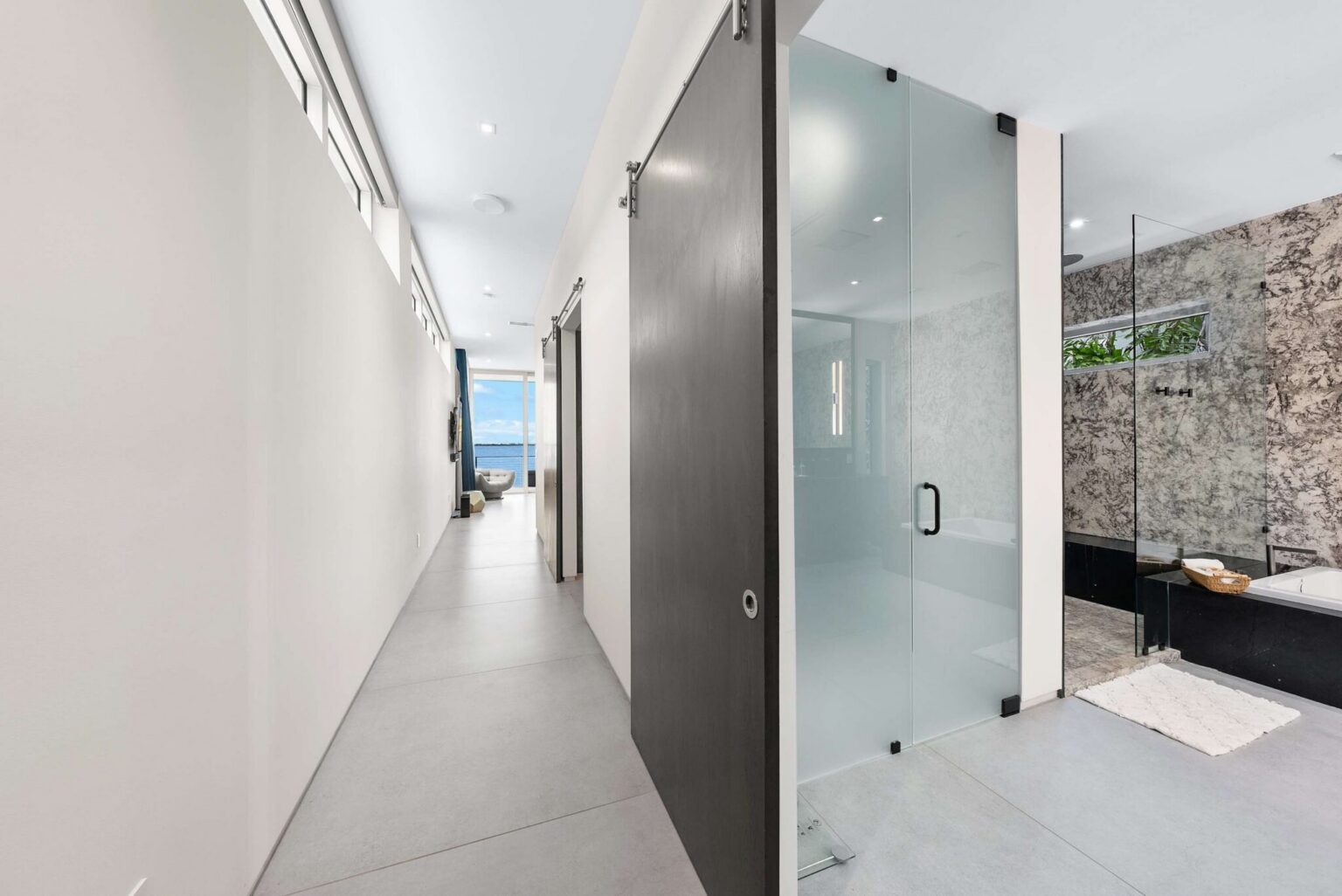 Contemporary elegance defines this private wellness space, featuring a glass-enclosed shower and sophisticated natural textures.