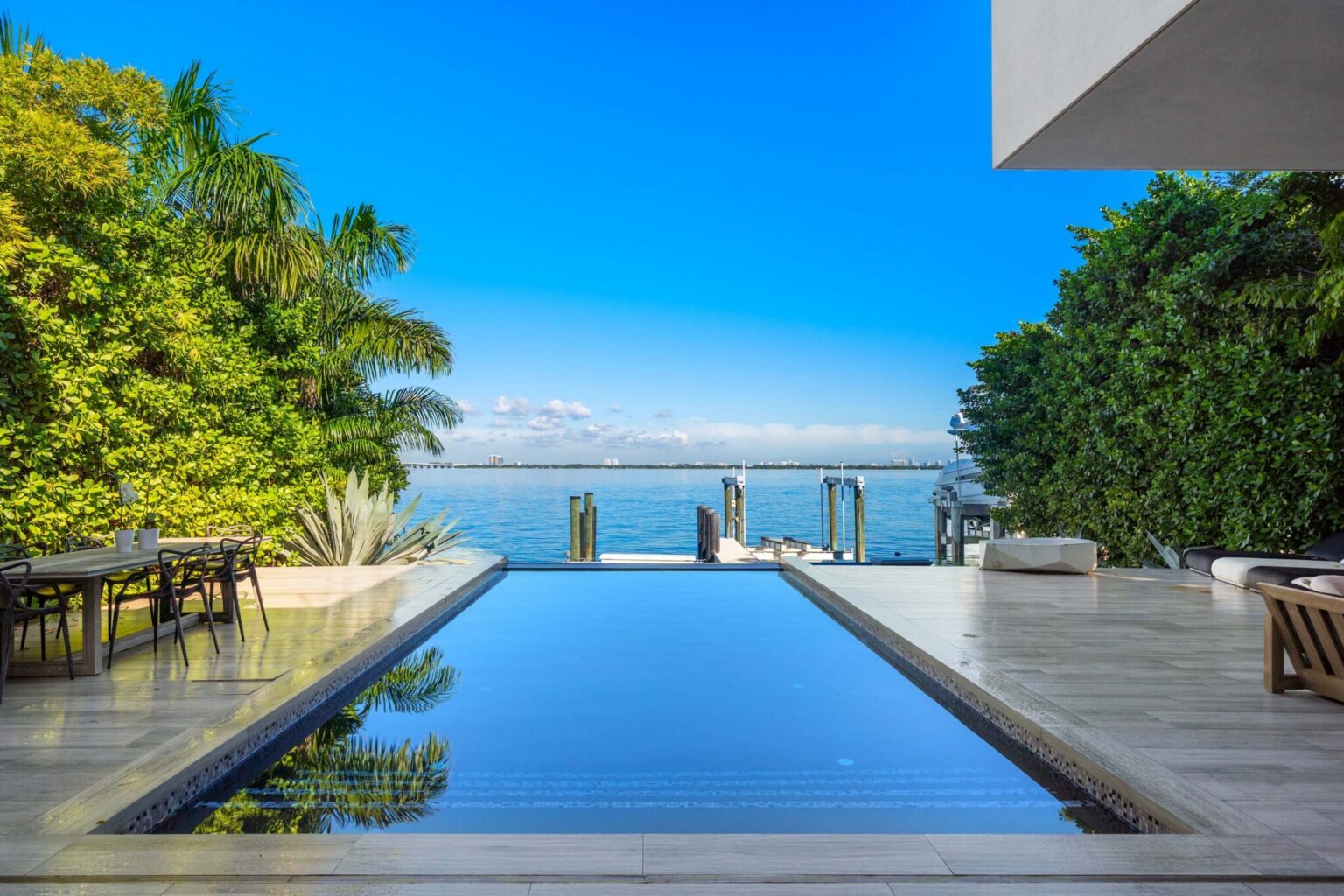 Waterfront pool overlooking the bay with private dock access, expansive sun deck, and tropical landscaping. Contemporary outdoor living space designed for lounging, dining, and enjoying unobstructed water views.