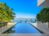 Waterfront pool overlooking the bay with private dock access, expansive sun deck, and tropical landscaping. Contemporary outdoor living space designed for lounging, dining, and enjoying unobstructed water views.
