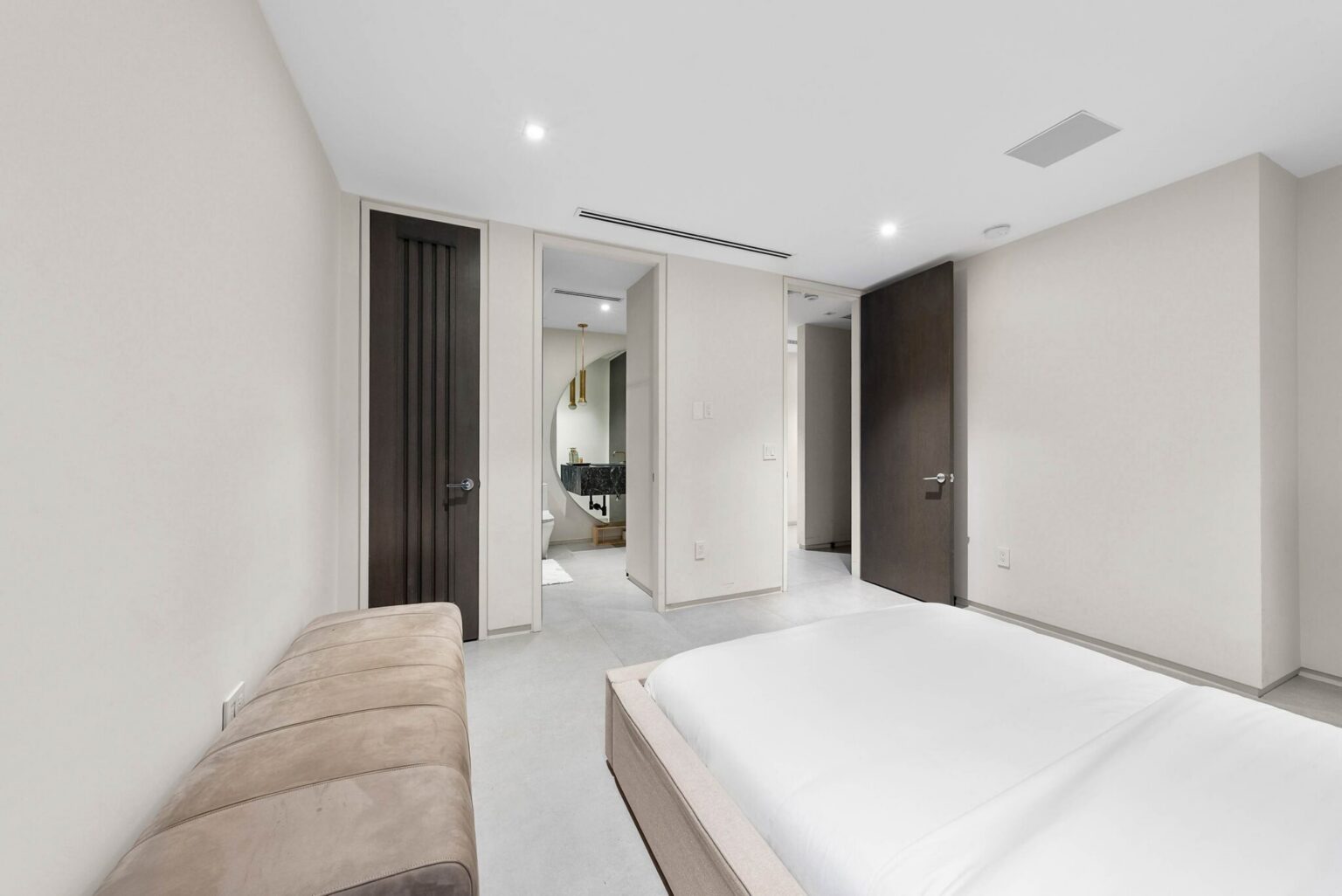 Spacious sleeping suite featuring a queen-size bed, ensuite bathroom access, built-in storage, and modern interiors. Tile flooring and a functional layout enhance guest comfort.