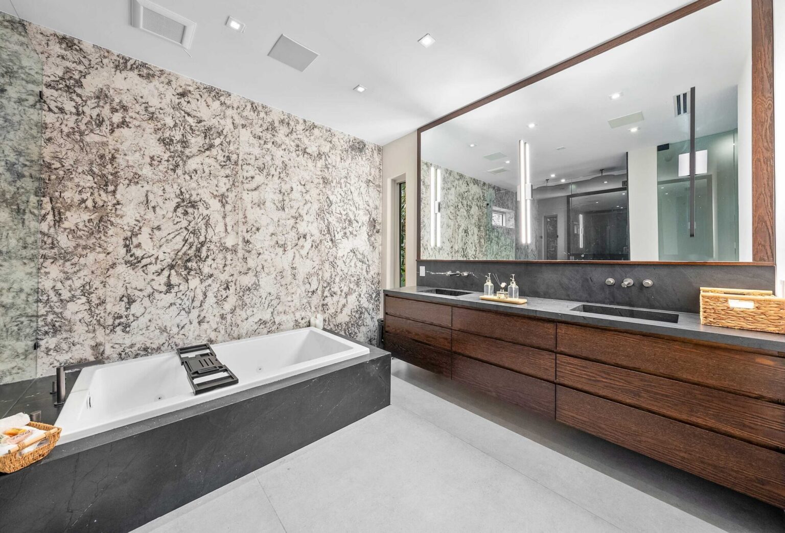 Elegant and expansive, the primary bath features custom double vanities, designer lighting, and a relaxing soaking tub.