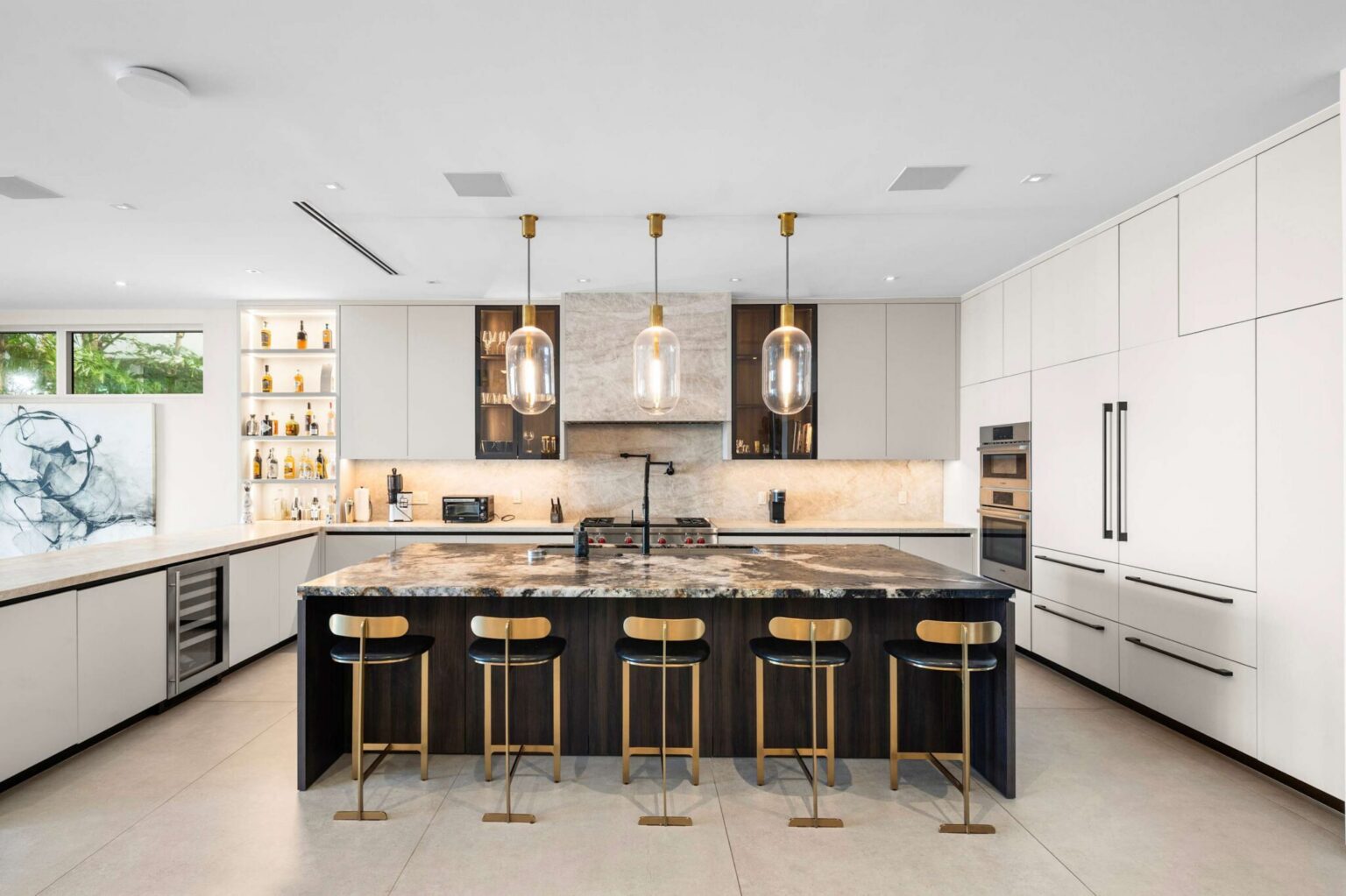 Modern culinary masterpiece with oversized island, elegant lighting, and luxury finishes.