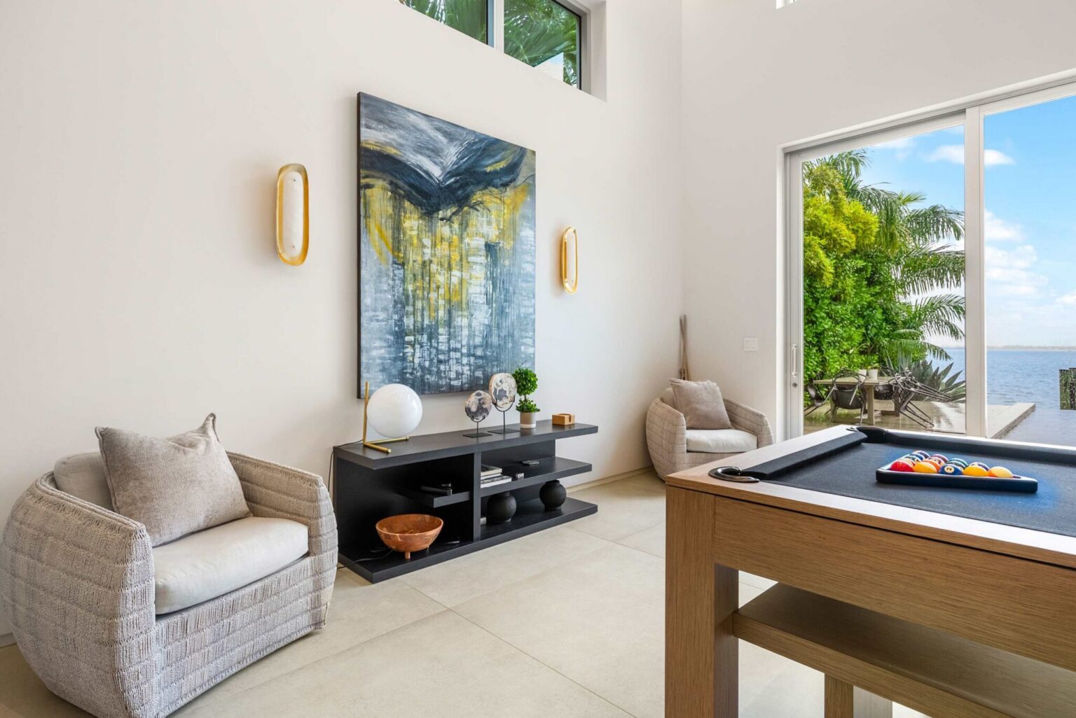 Elegant entertainment lounge with soaring ceilings, designer furnishings, and tranquil waterfront views.