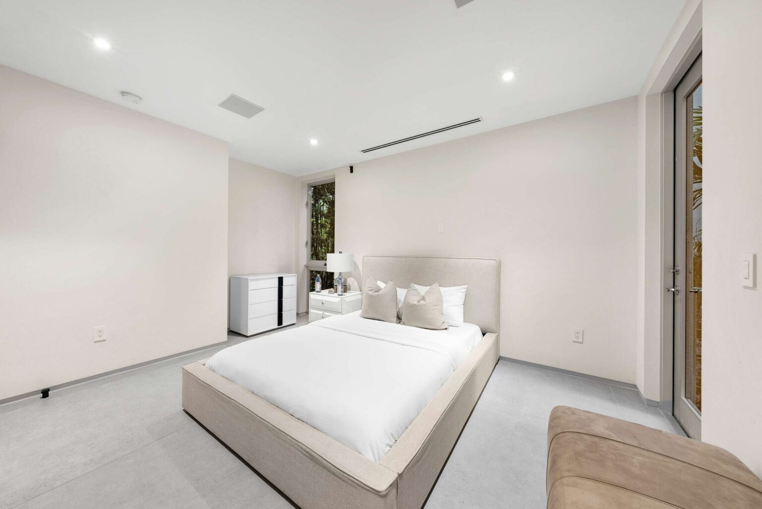 Contemporary sleeping suite featuring a queen-size bed, tile flooring, and modern furnishings. Clean architectural lines, natural light, and a spacious layout create a comfortable and private retreat within the home.
