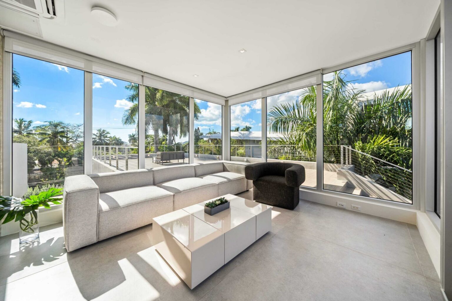 Sunlit corner retreat with floor-to-ceiling windows, lush tropical views, and modern elegance.