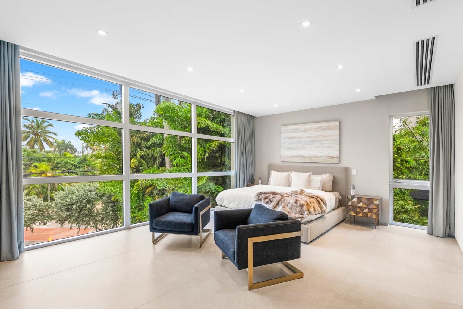 A stunning guest suite surrounded by lush tropical views, featuring floor-to-ceiling windows and sophisticated contemporary design.