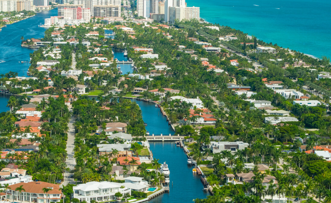 Aerial view of Miami waterfront homes with canals, lush landscaping, and Biscayne Bay.