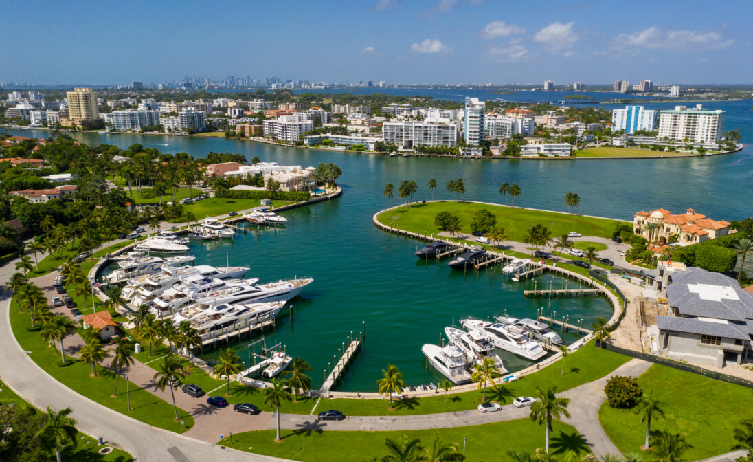 Aerial view of a Miami waterfront marina with yachts, turquoise water, and surrounding luxury residences.