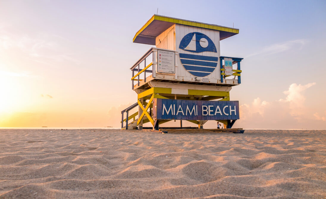 Miami Beach lifeguard tower on the sand at sunset with the Atlantic Ocean in the background.