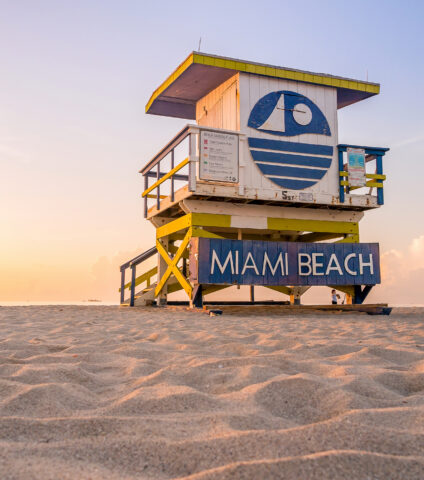 Miami Beach lifeguard tower on the sand at sunset with the Atlantic Ocean in the background.