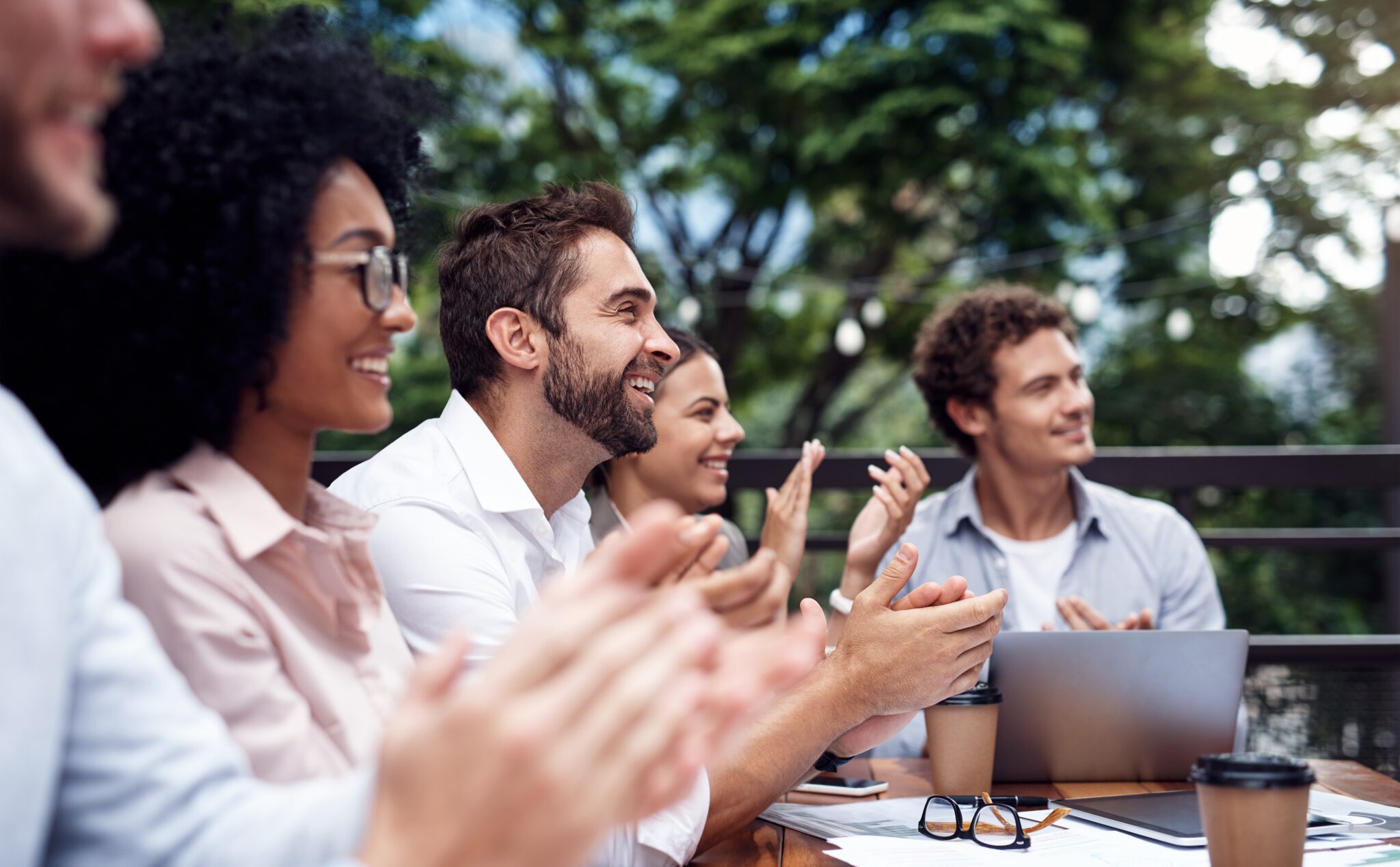 Business team collaborating during an outdoor meeting with a laptop in a relaxed setting.