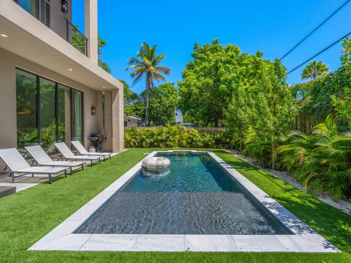 Backyard pool with sun loungers and grill