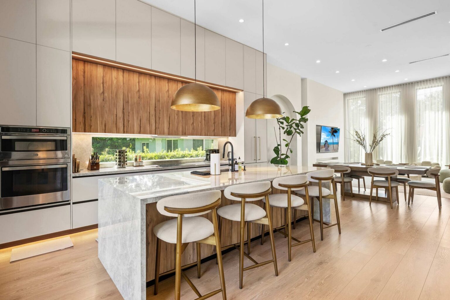 Open kitchen and dining area with marble island and brass pendants
