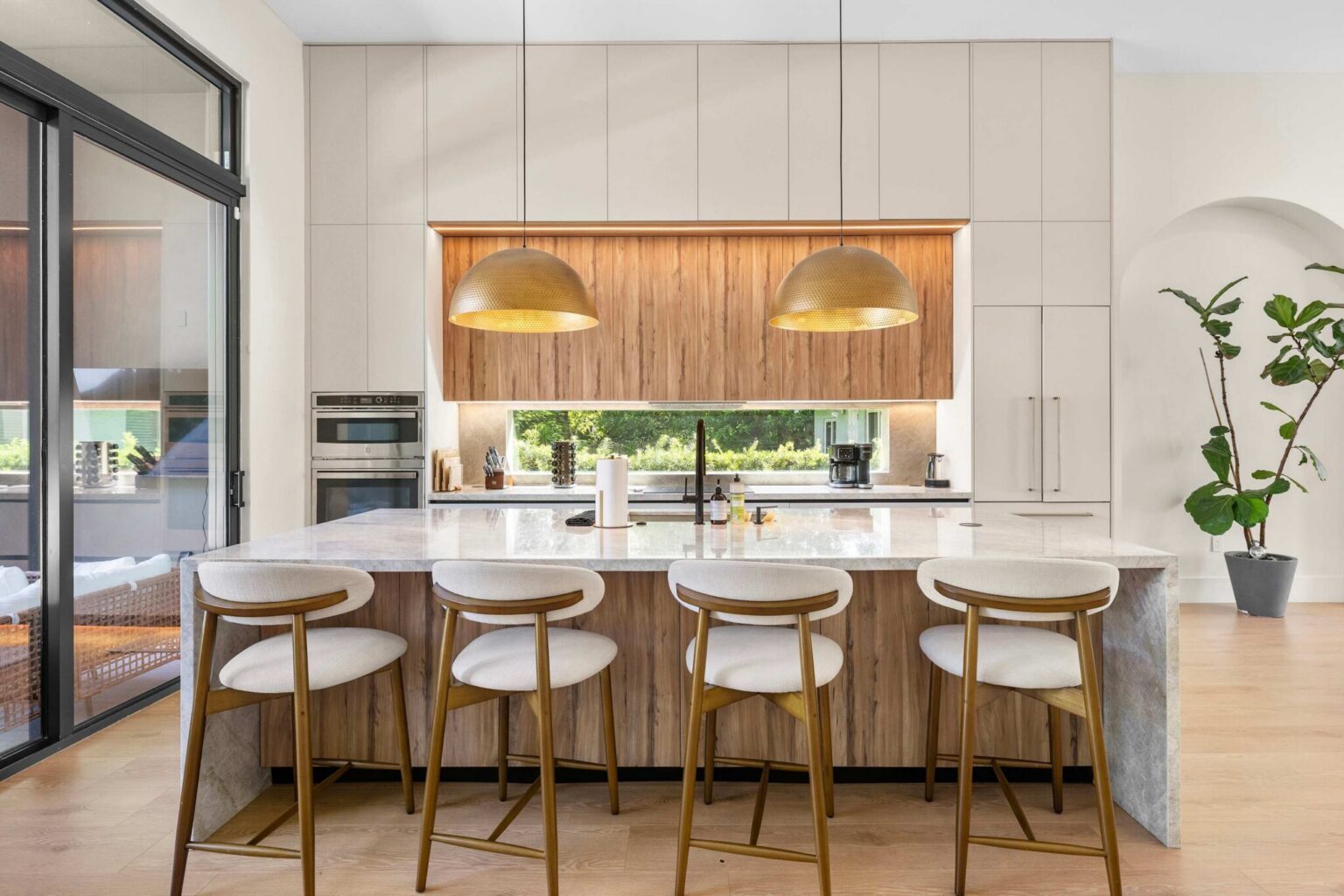 Marble island with bar seating under brass dome pendants