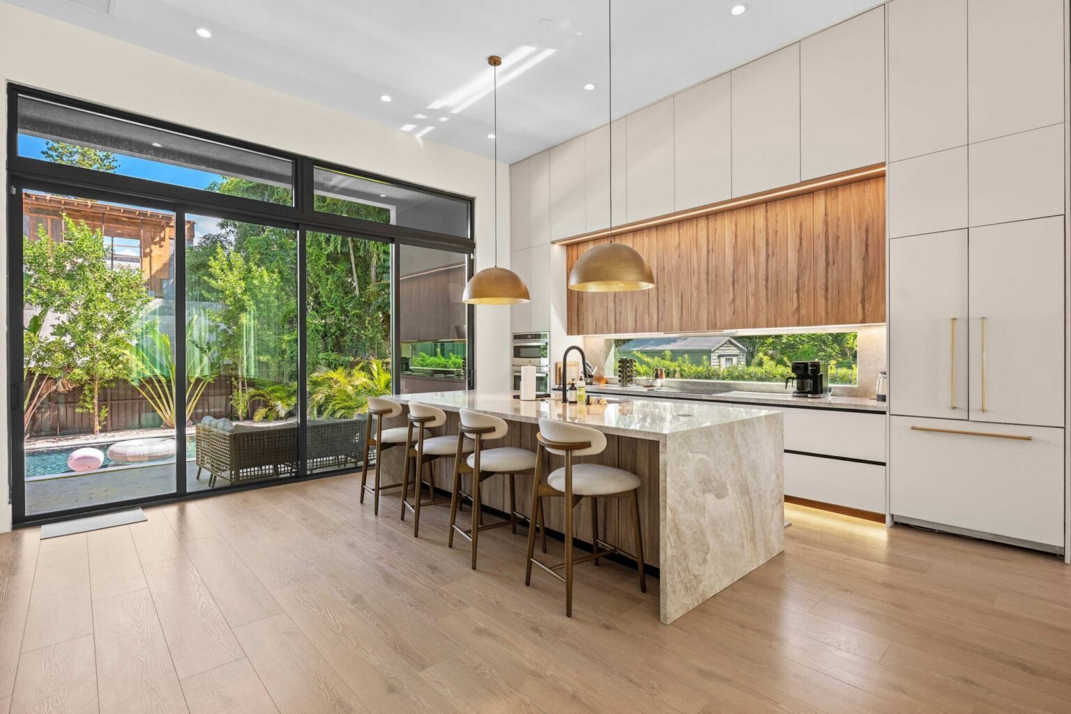 Designer kitchen with marble waterfall island and brass pendant lights