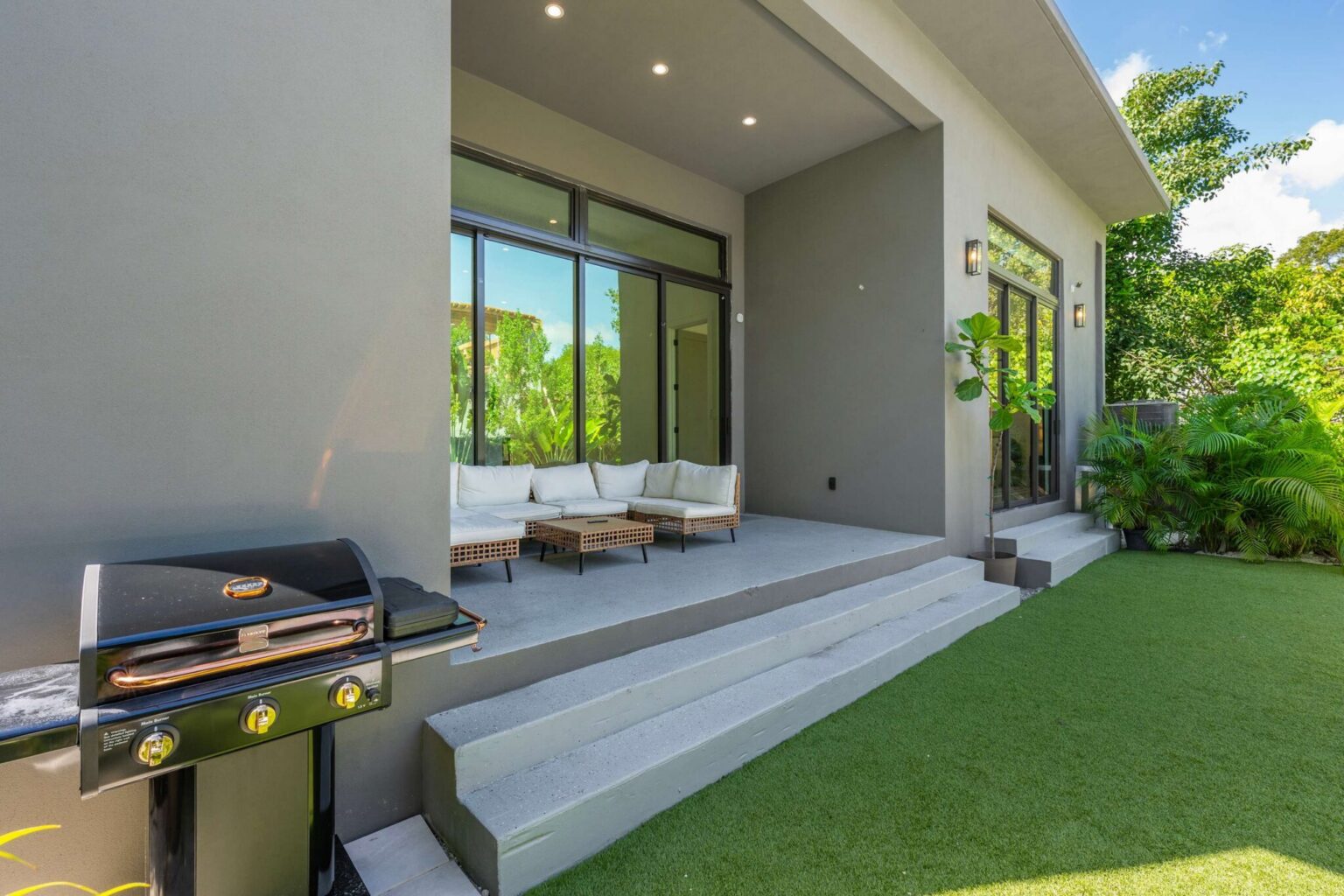 Built-in BBQ grill and covered terrace lounge in the tropical backyard