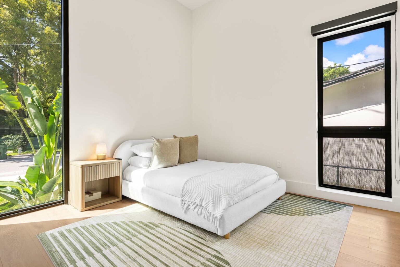 Bedroom with corner window and fluted nightstand