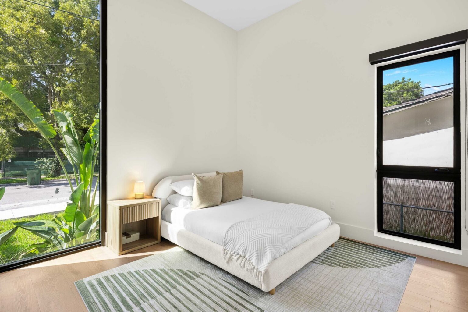 Bedroom with floor-to-ceiling corner window and tropical garden views