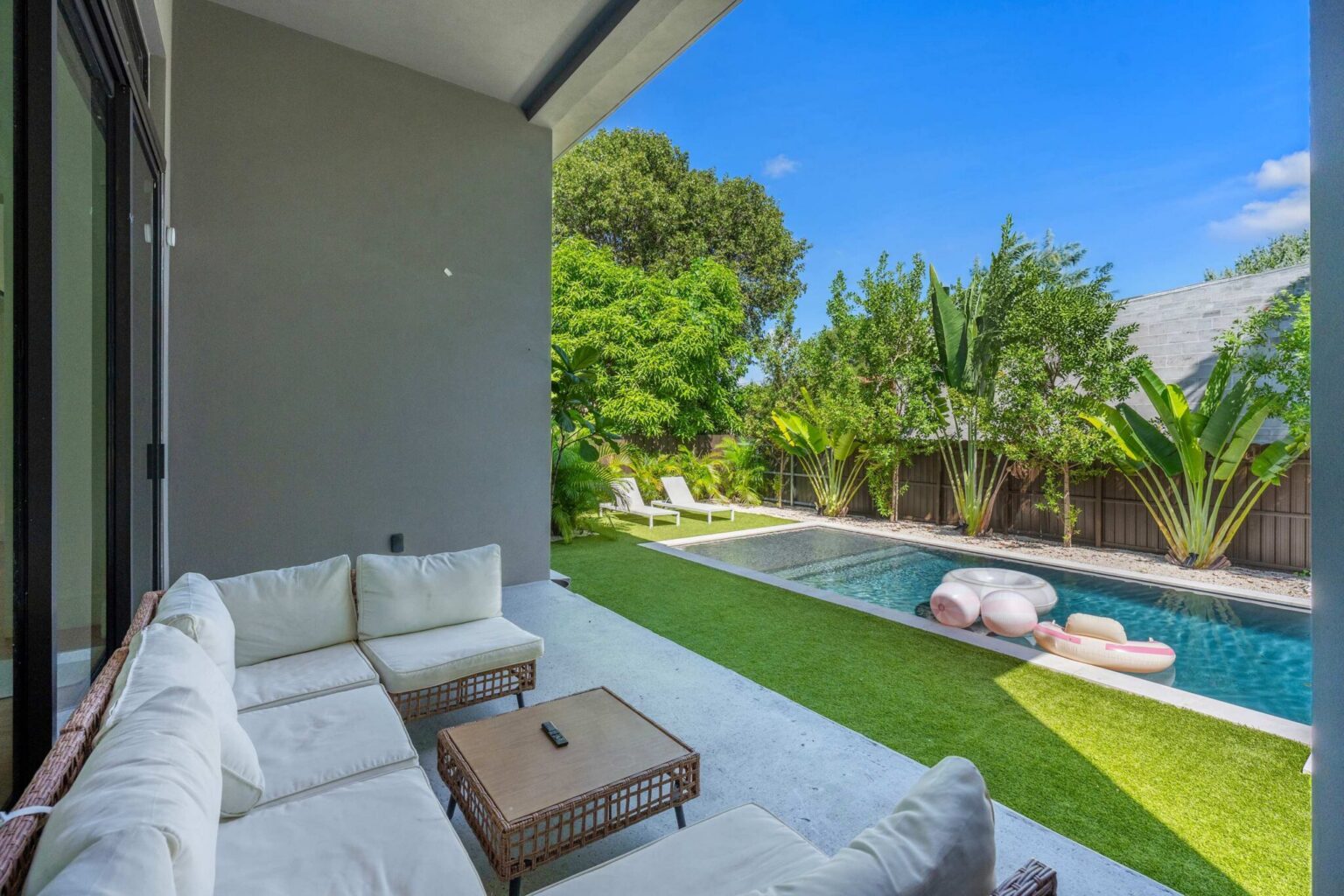 Covered terrace with wicker sectional sofa and pool views