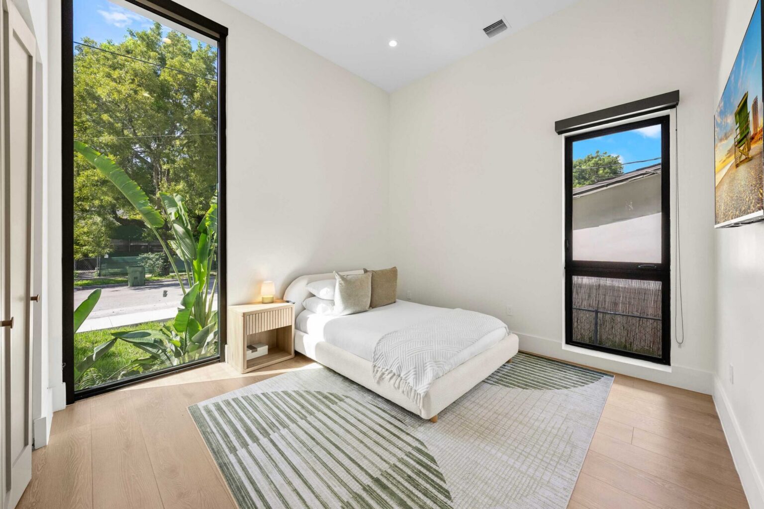 Corner bedroom with two windows and wall-mounted TV